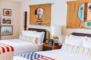 two beds in a hotel room with paintings on the wall at Graduate by Hilton Tempe in Tempe