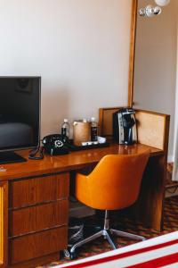a desk with a television and a chair in a room at Graduate by Hilton Tempe in Tempe