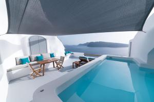 a villa with a swimming pool and a table and chairs at Maregio Suites in Oia