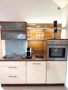 TinyHouse Pfalzperle Auszeit nahe Deutsche Weinstraße & Therme في Ellerstadt: مطبخ بخزائن بيضاء وفرن موقد