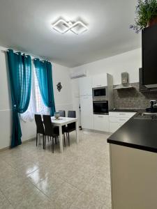 a kitchen with a table and chairs and blue curtains at angi home in Arma di Taggia