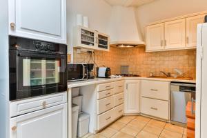 eine Küche mit weißen Schränken und schwarzen Geräten in der Unterkunft La Cabane Rouge - Wifi - Parking in Les Bussolleries