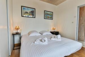 ein Schlafzimmer mit einem großen weißen Bett mit Handtüchern darauf in der Unterkunft La Cabane Rouge - Wifi - Parking in Les Bussolleries