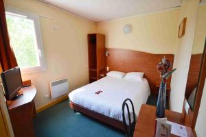 ein Hotelzimmer mit einem Bett, einem Schreibtisch und einem TV in der Unterkunft Adams Hotel in Metz