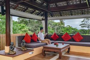 a man sitting on a couch in a living room with red pillows at Villa SALSA PRIVATE POOL in Ko Yao Noi