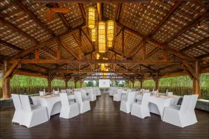 un largo salón de banquetes con mesas blancas y sillas blancas en Six Senses Qing Cheng Mountain, en Chengdú