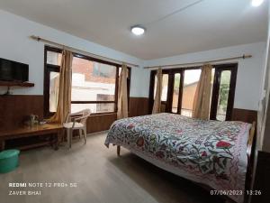 a bedroom with a bed and a desk and windows at Hotel Adnan Palace in Pahalgām
