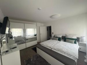 a white bedroom with a bed and a television at Ferienwohnung Melanie 300 Meter zur Therme in Bad Ems