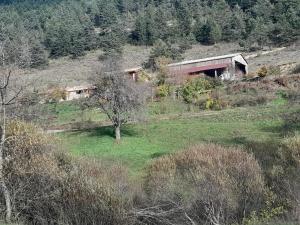 a building on a hill with a field and trees at Maison isolée tout équipée in La Piarre