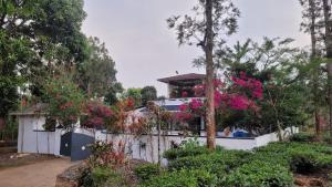 a house with a white fence and pink flowers at Jungle Tusker Resort The Nilgiris in Pandalūr