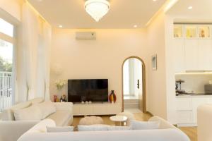 a living room with white furniture and a flat screen tv at Our Home in Da Lat
