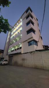 a tall white building with a car in front of it at Shree Vitthal Bhakt Nivas, Pandharpur in Pandharpur +1 photo
