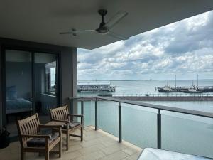 a balcony with two chairs and a view of the ocean at Waterfront Getaway Darwin City in Darwin
