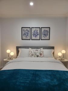 a bedroom with a large bed with three pictures on the wall at BJ Holiday House in Chittaway Point