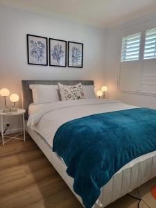 a bedroom with a large bed with a blue blanket at BJ Holiday House in Chittaway Point