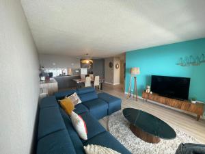 ein Wohnzimmer mit einer blauen Couch und einem Fernseher in der Unterkunft L'air Marin Clim&Parking in Sète