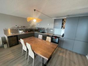 eine Küche mit einem Holztisch und weißen Stühlen in der Unterkunft L'air Marin Clim&Parking in Sète