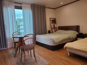 a bedroom with a bed and a table and chairs at Seogwipo The Hyeyum Stay in Sangye-ri +33 photos