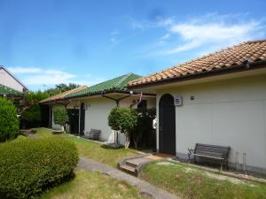 a white house with a bench in the yard at Tabi No Yado Harusame in Kumano