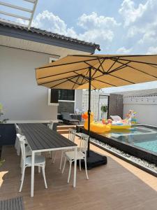 a patio with a table and chairs and a pool at The Wing Pool Villa Surin in Surin