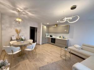 a living room and kitchen with a table and chairs at SILK Apartman -free private garage in Nyíregyháza