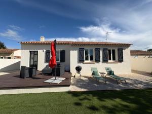 a house with a deck with two chairs and a red umbrella at Maison Aiméo en Camargue in Arles