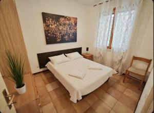 a bedroom with a white bed and a chair at Cacciatore in Rosolina