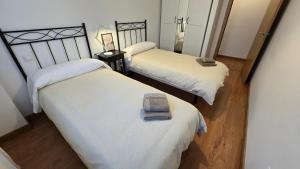 two beds in a room with white sheets at Apartamento Cantabria Verde in Los Corrales de Buelna