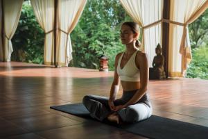 a woman sitting in a yoga pose on the floor at Hot Stone Club Ubud in Ubud