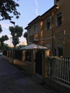 un bâtiment avec un parasol à côté d'une clôture dans l'établissement Villa Grazia, à Rimini