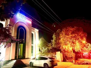 a white car parked in front of a building at Mia Garden Hotel in Dinh Ðiền Buôn Hô