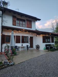 ein weißes Haus mit einer Terrasse und einem Sonnenschirm in der Unterkunft La Dolce Vita. Alloggio nel verde cuore del Friuli Venezia Giulia in Mariano del Friuli