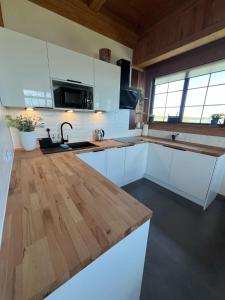 a kitchen with white cabinets and a wooden counter top at Willa Różowy Domek in Rakowice Małe +24 photos