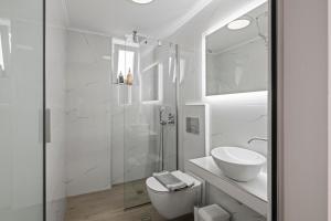 a white bathroom with a shower and a sink at Dora Apartments in Agia Pelagia +46 photos