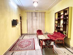 a living room with red chairs and a table at Jai Villa Homestay in Prayagraj