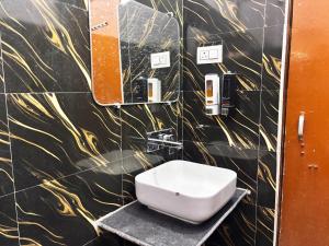 a toilet in a bathroom with a black and gold wall at Jai Villa Homestay in Prayagraj +29 photos