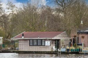 莱茵河畔阿尔芬Aangenaam op de Rijn, woonboot, inclusief privé sauna的河岸边的房屋