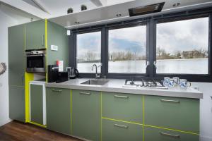 莱茵河畔阿尔芬Aangenaam op de Rijn, woonboot, inclusief privé sauna的一个带绿色橱柜和大窗户的厨房