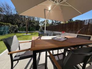 a wooden table with an umbrella on a patio at Poggio Mezzana T2 climatisé avec jardin proche mer in Poggio-Mezzana