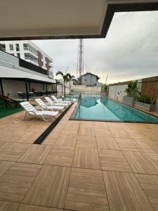 a swimming pool with white lounge chairs on a building at Apartamento completo em Salinópolis in Salinópolis