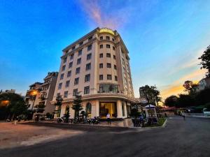 a large white building with motorcycles parked in front of it at Lotus Hotel & Apartment in Hai Phong