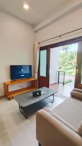 a living room with a couch and a tv at 2-Bedroom Maduea Wan House in Ko Phangan