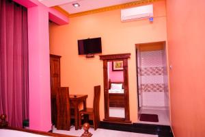 ein Zimmer mit einem Fernseher, einem Tisch und einem Spiegel in der Unterkunft VictoriaPalace in Colombo