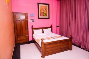 ein Schlafzimmer mit einem Bett mit einer rosa Wand in der Unterkunft VictoriaPalace in Colombo
