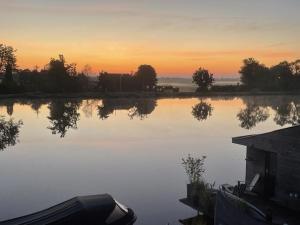莱茵河畔阿尔芬Aangenaam op de Rijn, woonboot, inclusief privé sauna的一大片水体,背景是日落
