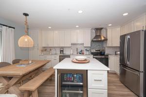 a white kitchen with a table and a refrigerator at Tranquil 2-Bedroom Condo in Hidden Bay Relax & Enjoy Bay Views in Ocean City