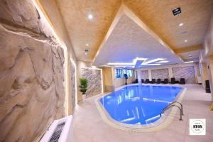 una gran piscina en un edificio con una pared de piedra en Atos lux & spa Zlatibor, en Zlatibor