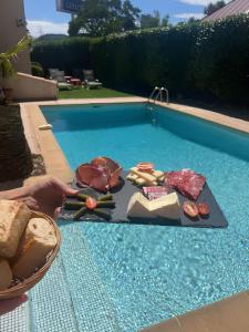 a table with meat and vegetables next to a swimming pool at Adonis Arc Hotel Aix in Aix-en-Provence
