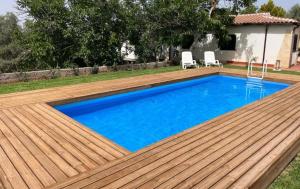 a swimming pool with a wooden deck and blue water at Villa con piscina a due passi da Siracusa in Canicattini Bagni