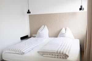 un letto bianco con lenzuola e cuscini bianchi di Das Stadthouse 2 a Gunskirchen